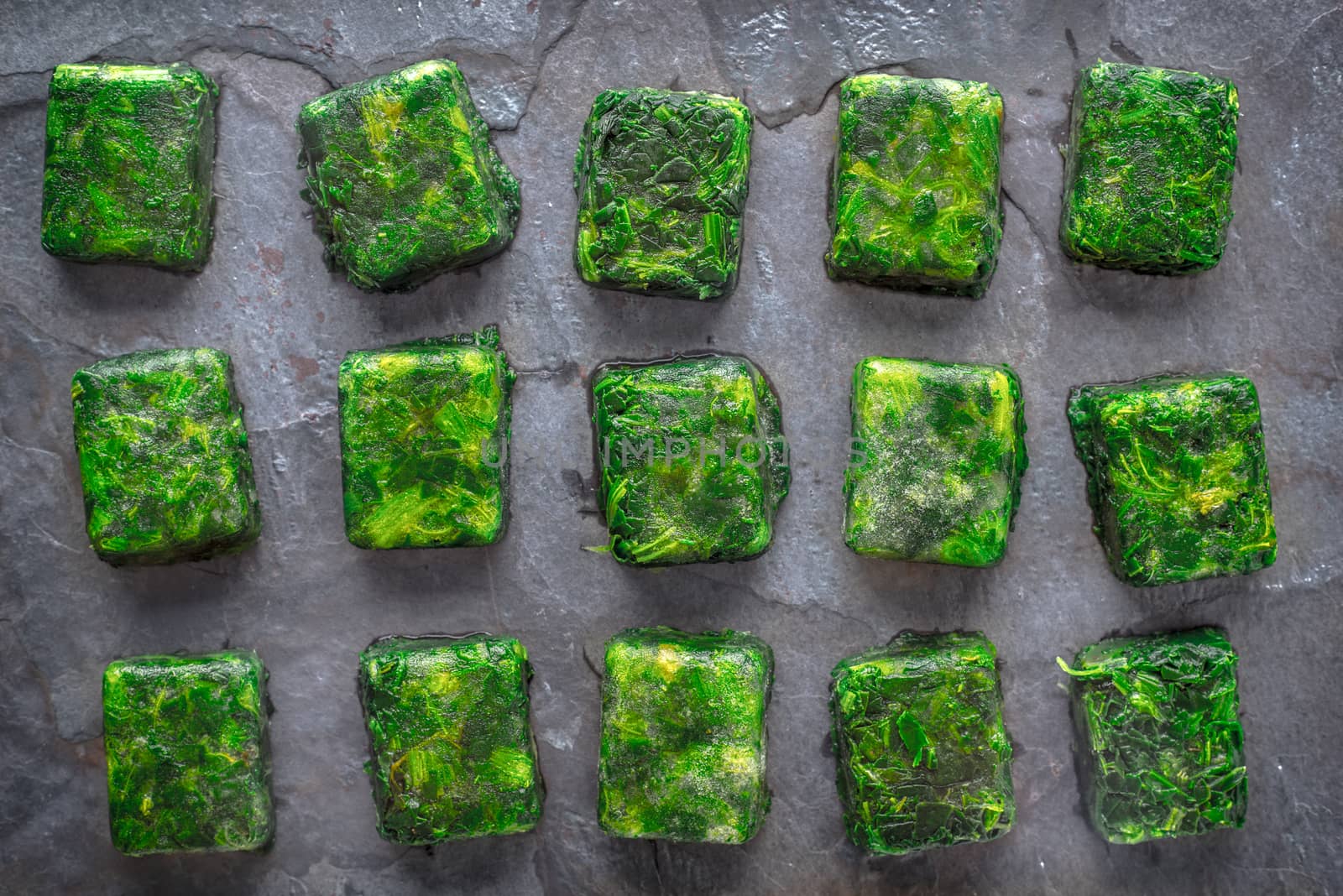 Cubes of frozen spinach on the stone table top view by Deniskarpenkov