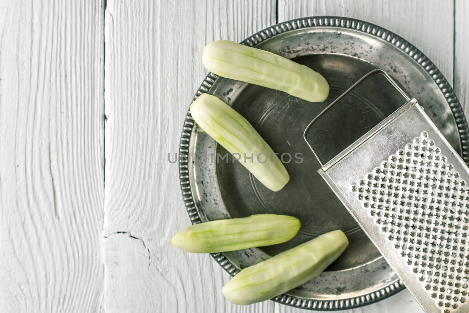 Peeled cucumbers in the metal plate with grater horizontal by Deniskarpenkov