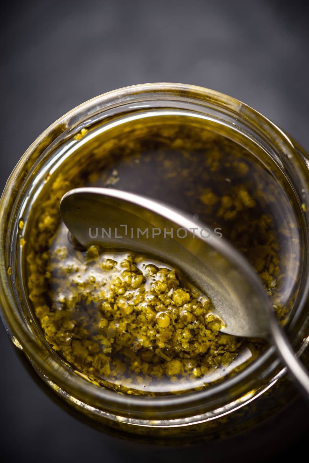 Pesto sauce in the glass jar with spoon vertical by Deniskarpenkov