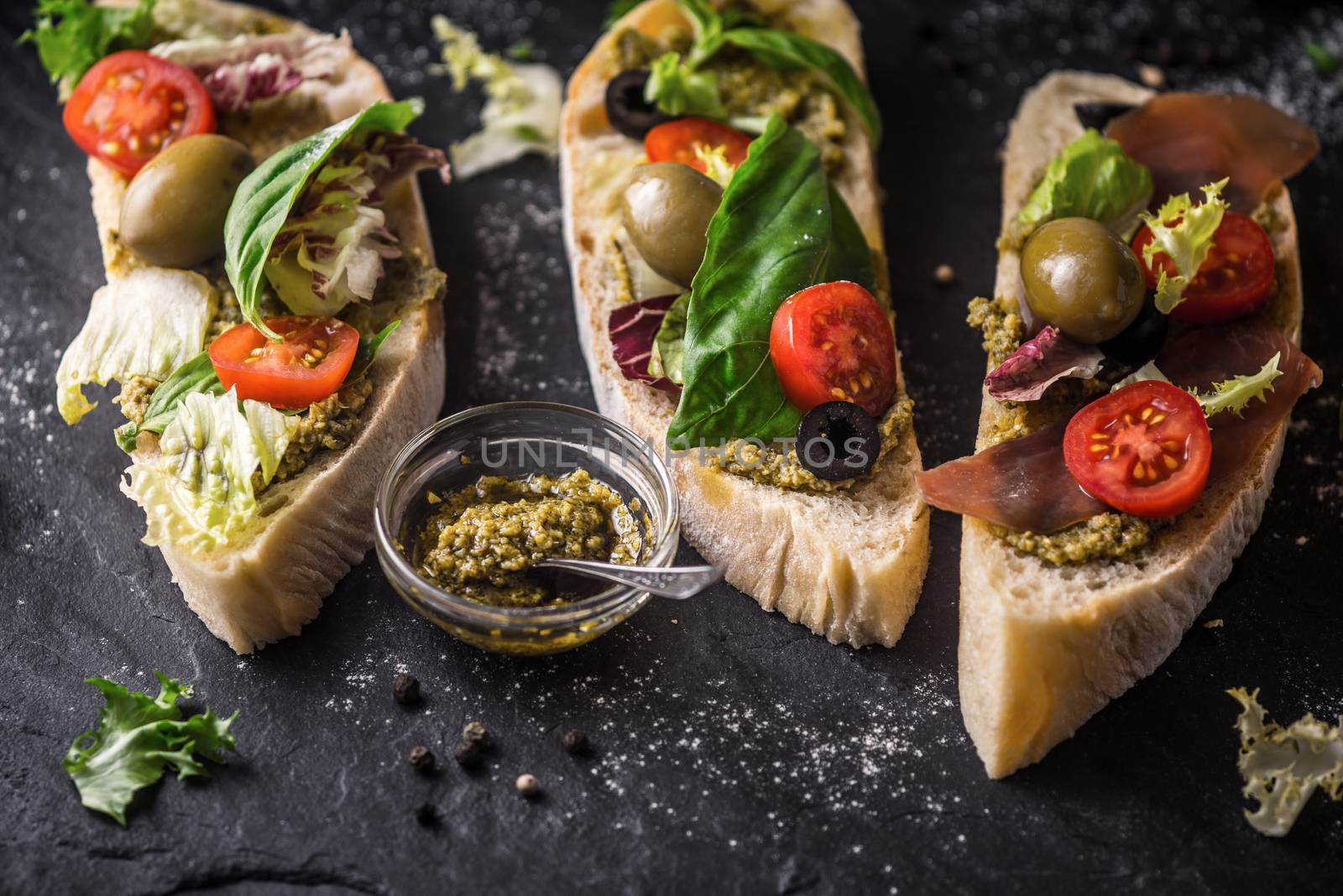 Ciabatta with olives , tomatoes and basil on the black stone table by Deniskarpenkov