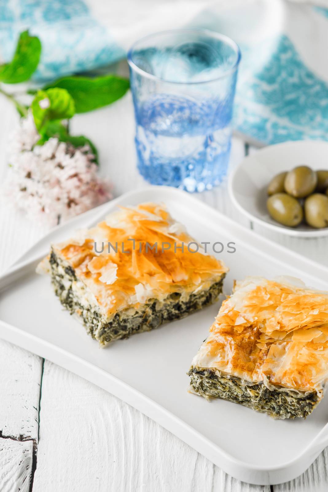 Greek pie spanakopita on the white plate with accessorizes vertical by Deniskarpenkov