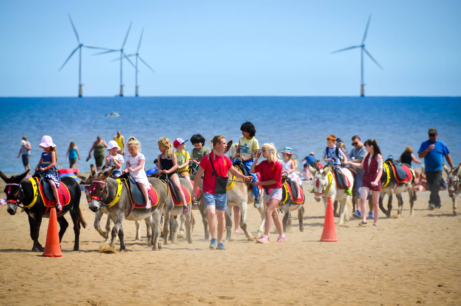 Skegnes-England July-2016 photo taken on the beach shows children riding on donkey with supervisor. Editorial photo