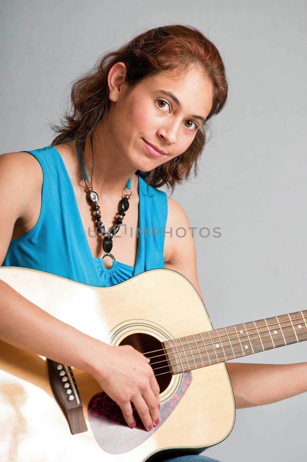 Pretty multi-ethnic brunette playing a acoustic guitar