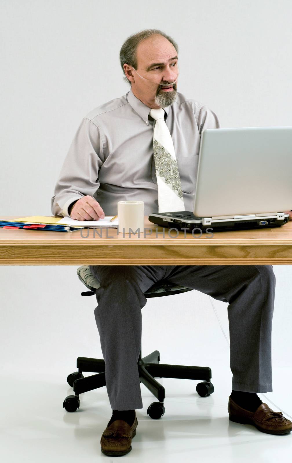 Businessman with a breathing disability seated at his desk with a laptop.