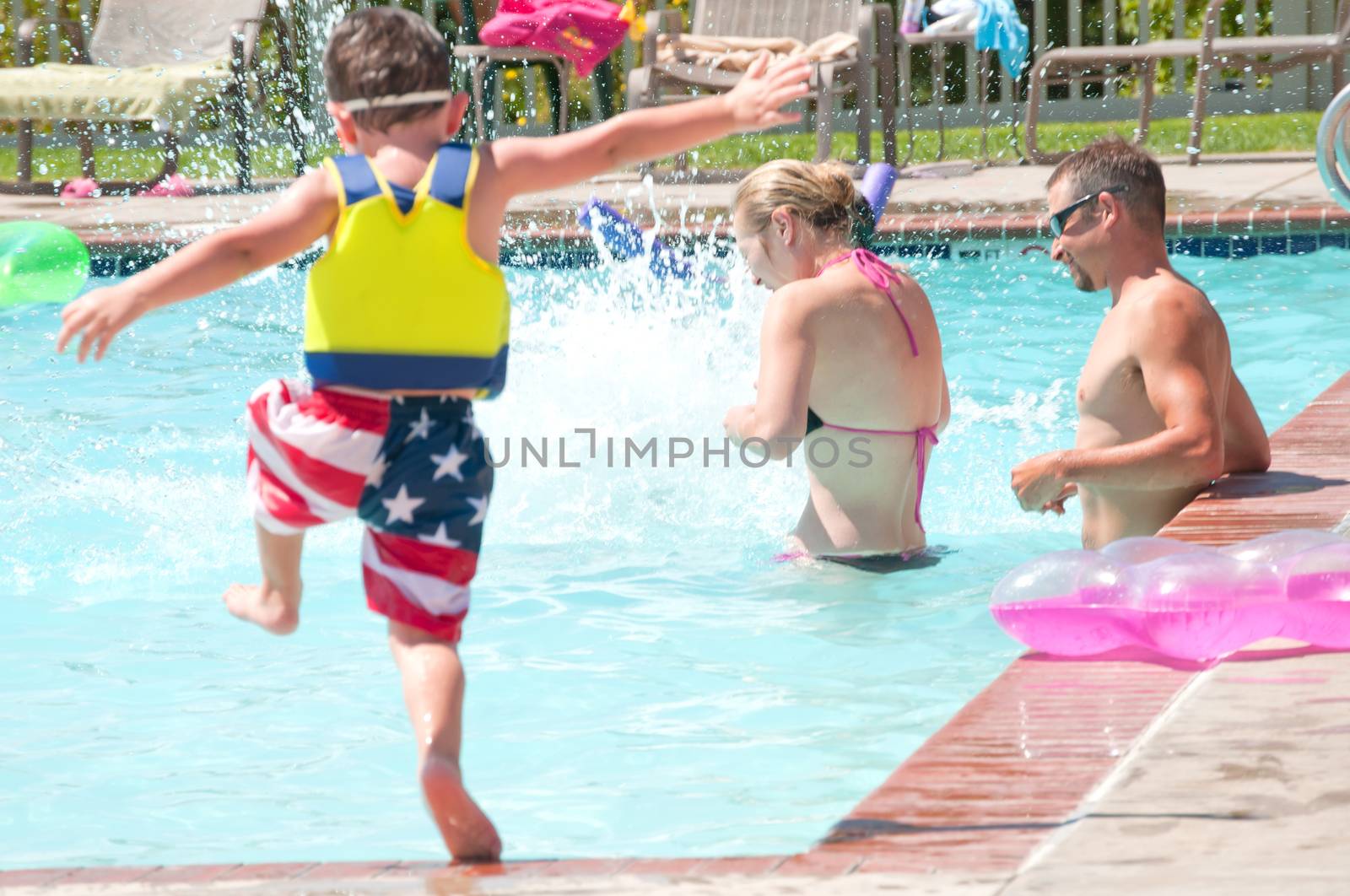 Young Parents enjoying time at the swimming pool with their children.