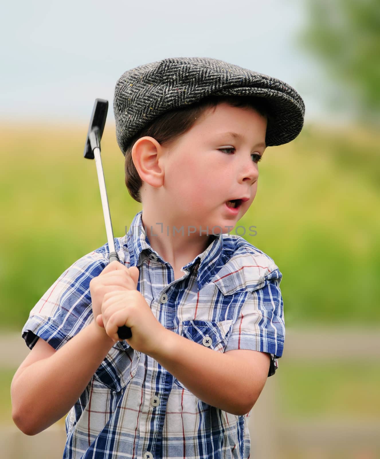 Cute little boy in a driving hat playing with a golf club