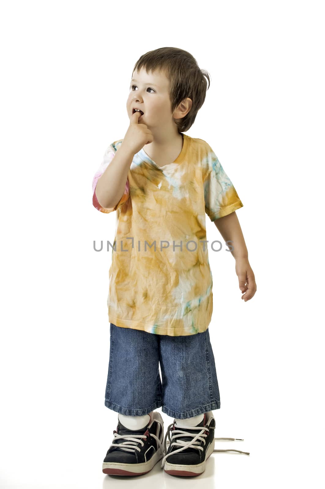 Baby boy trying on his brothers tennis shoes. They are still too large. Photographed against a white background