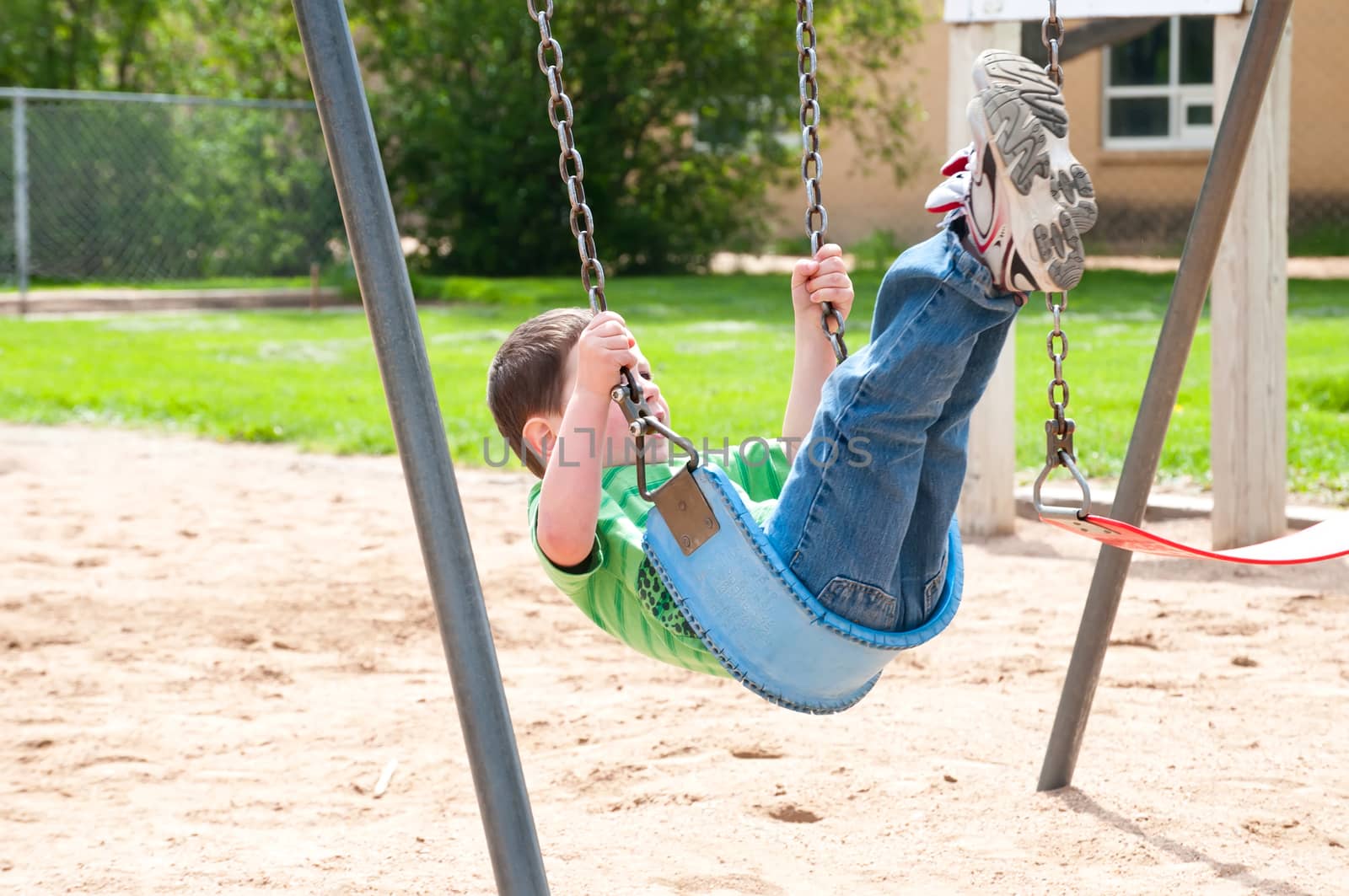 Little boy enjoying the swings at the city park.