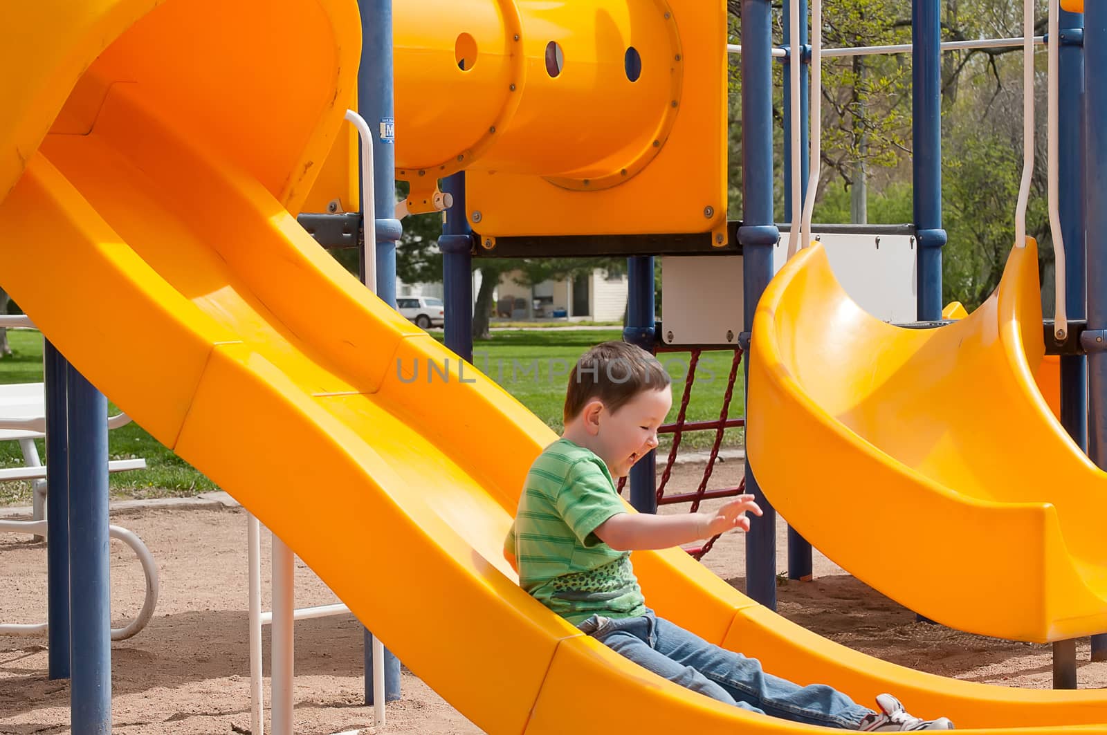 Little boy enjoying the playground equipment at the city park.