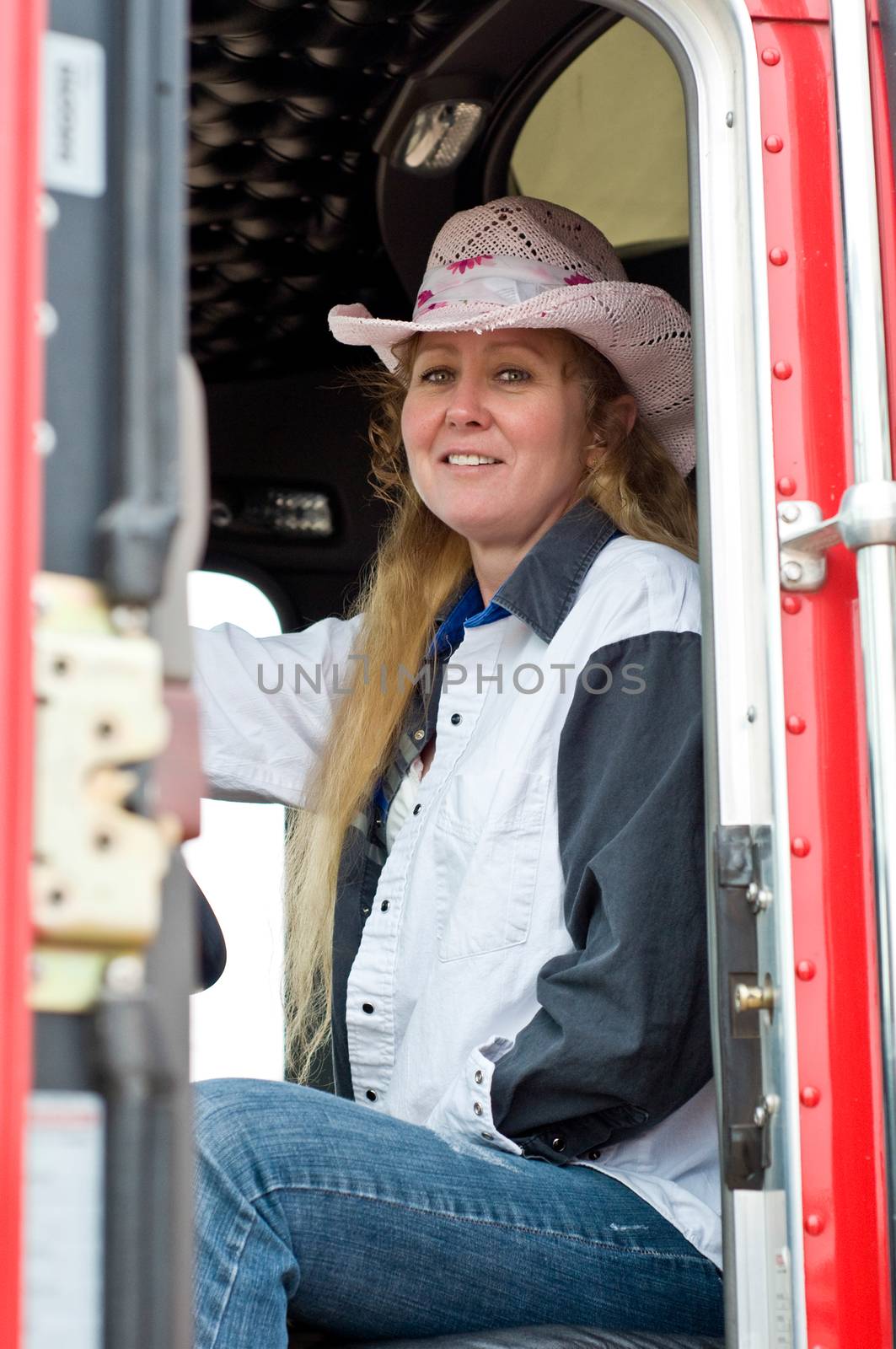 Woman truck driver ready to start her run with a loaded trailer behind a semi-truck.