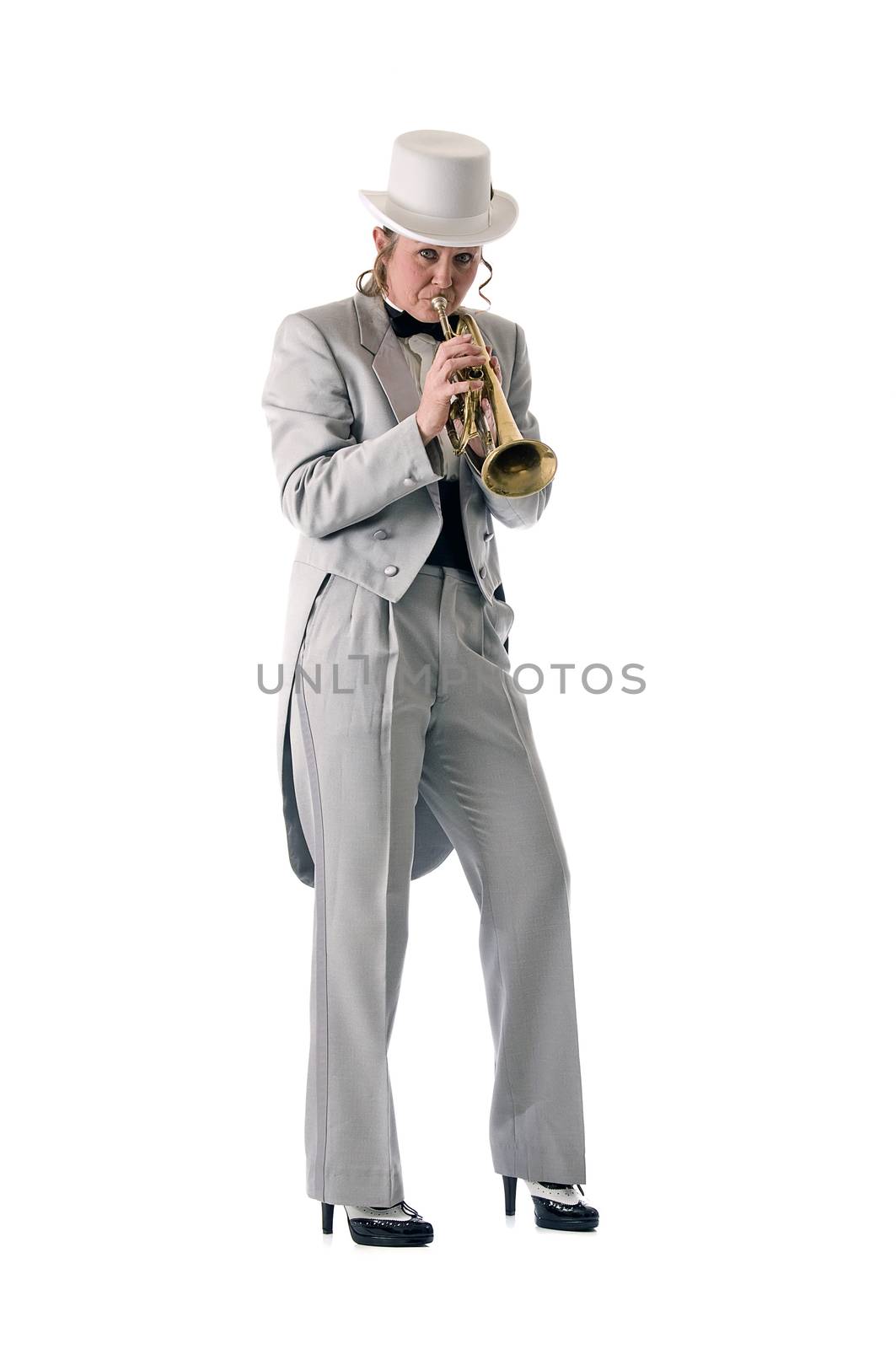 Pretty blonde woman in tuxedo and top-hat playing a trumpet while standing.