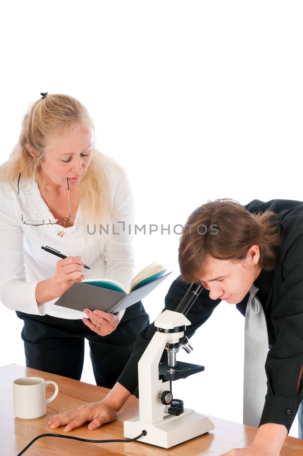 Female professor teaching a male student in a biology class, using a microscope. Isolated on a white background.