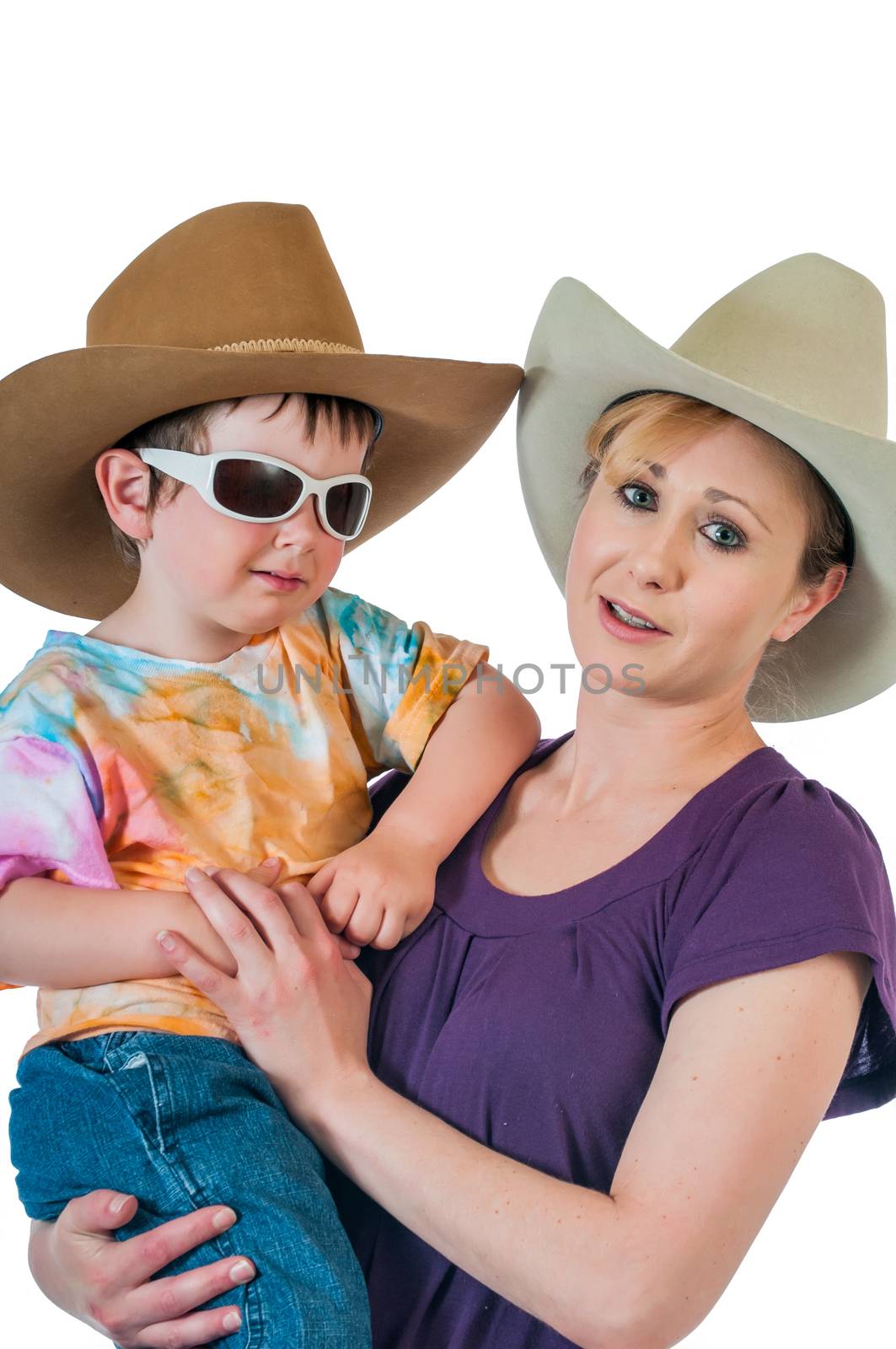 Pretty young cowgirl holding her little cowboy. Isolated against a white background.