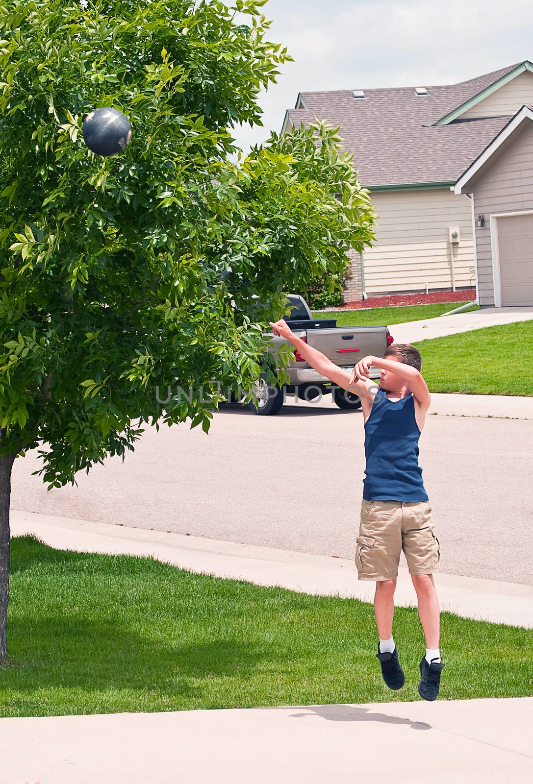 Teenage boy shooting a basketball at his home practice hoop