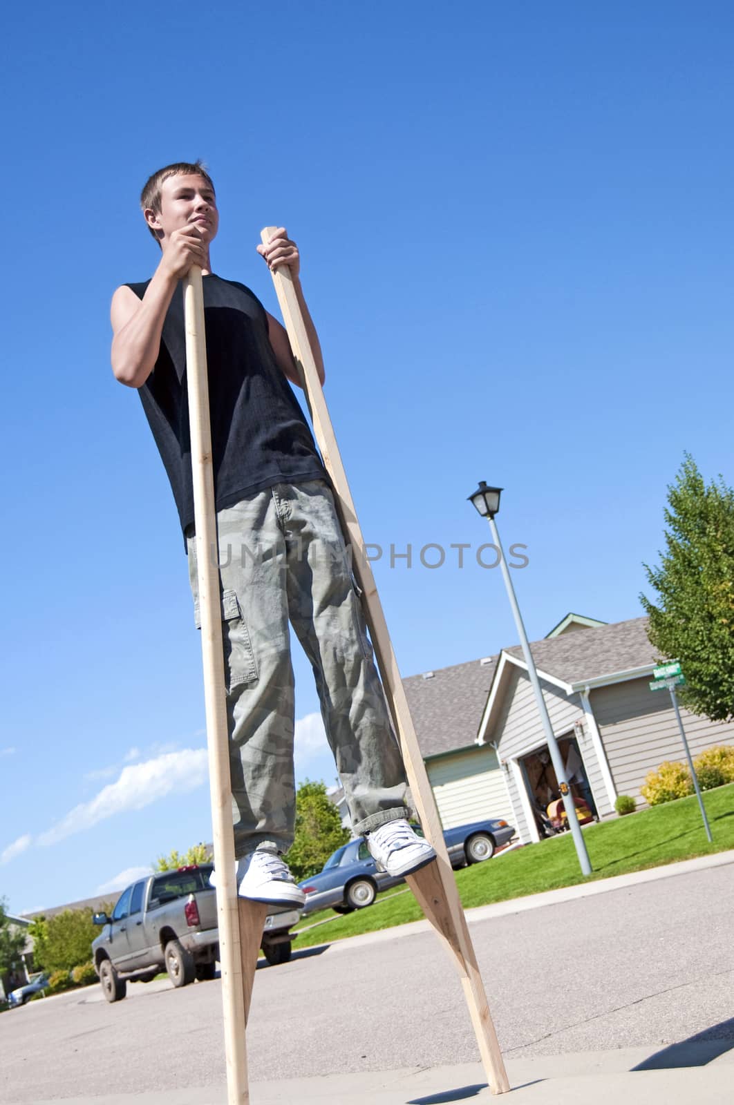 Teenage boy using stilts to walk around the neighborhood.