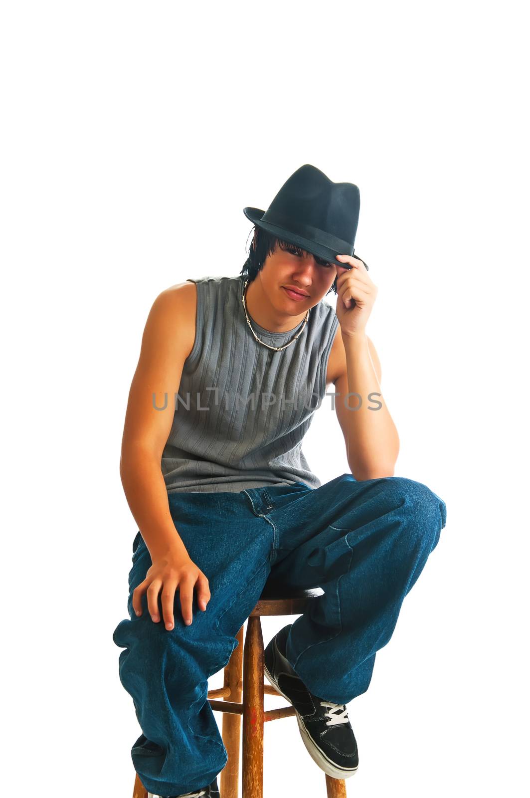 Handsome young man sitting cool in a fedora on a stool. Isolated on a white background.