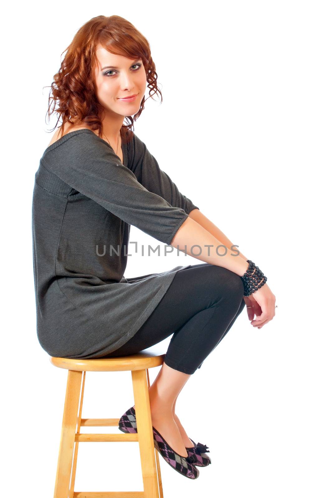 Beautiful young woman seated on a kitchen stool against a white background