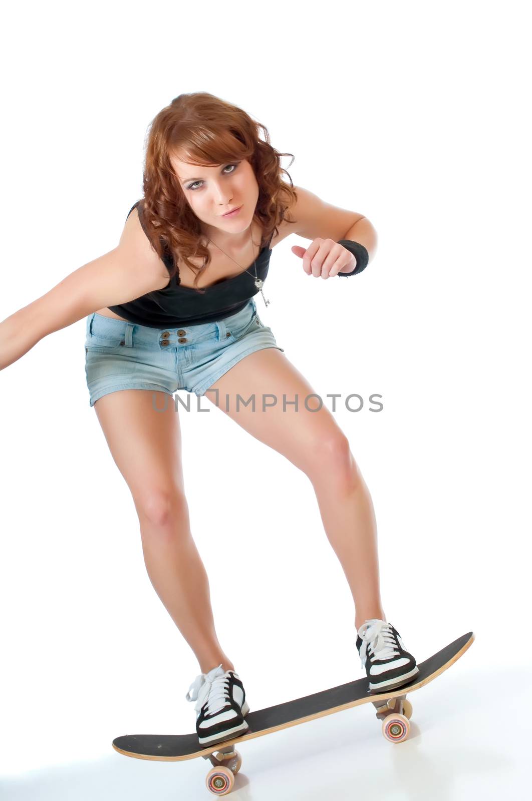 Beautiful young woman riding a skateboard against a white background