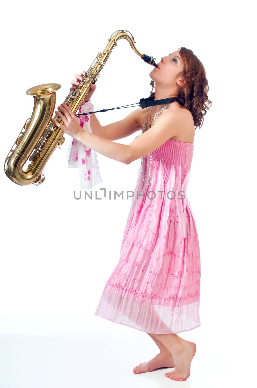 Barefoot girl playing jazz on a tenor saxophone against a white background.