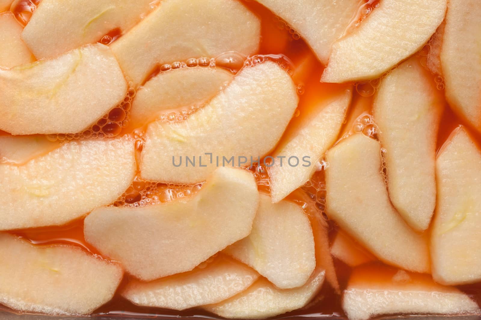 Red wet apple slices within a fruit punch. Food background