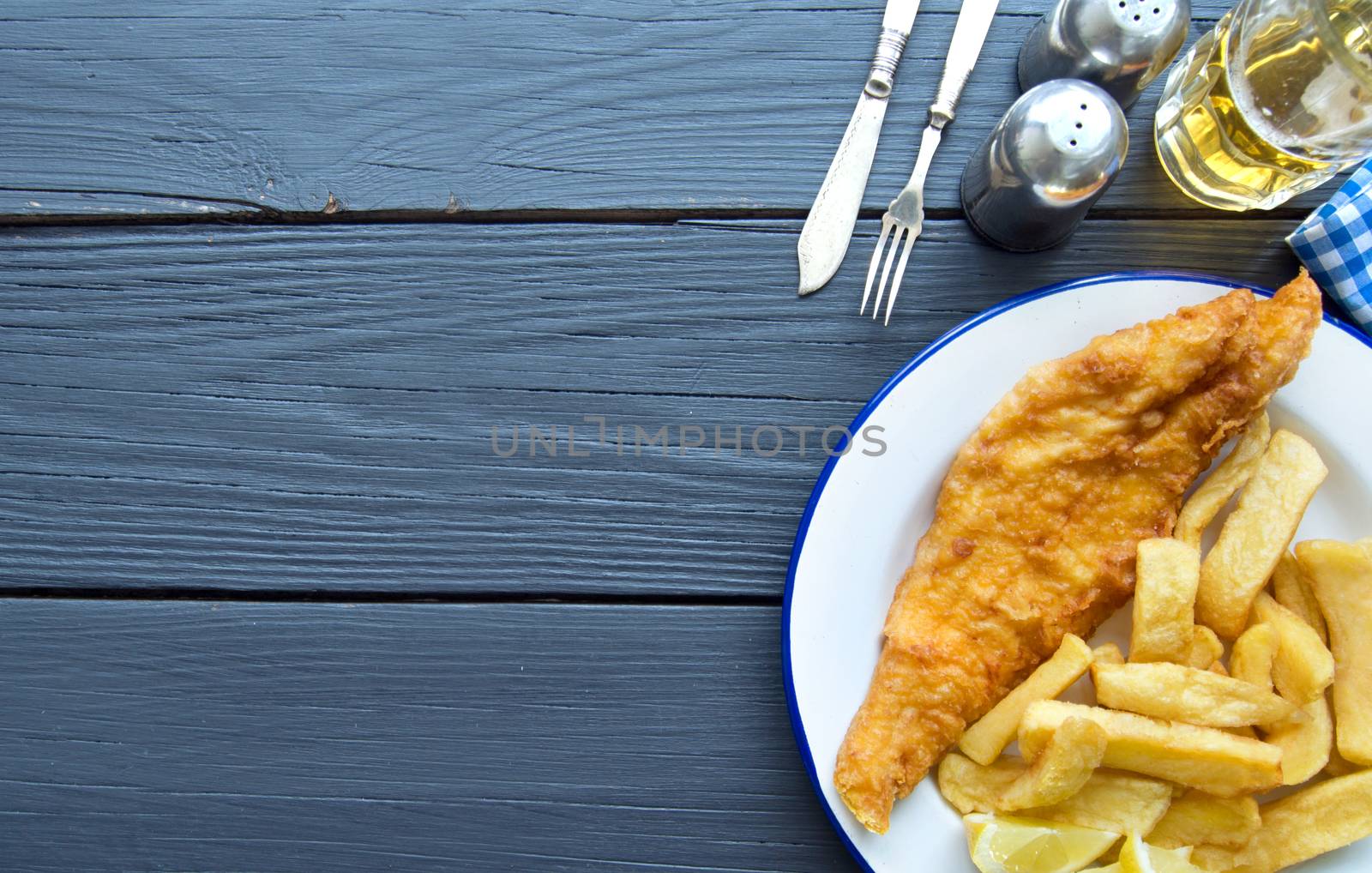 Deep fried fish and chips on a wooden table with space 