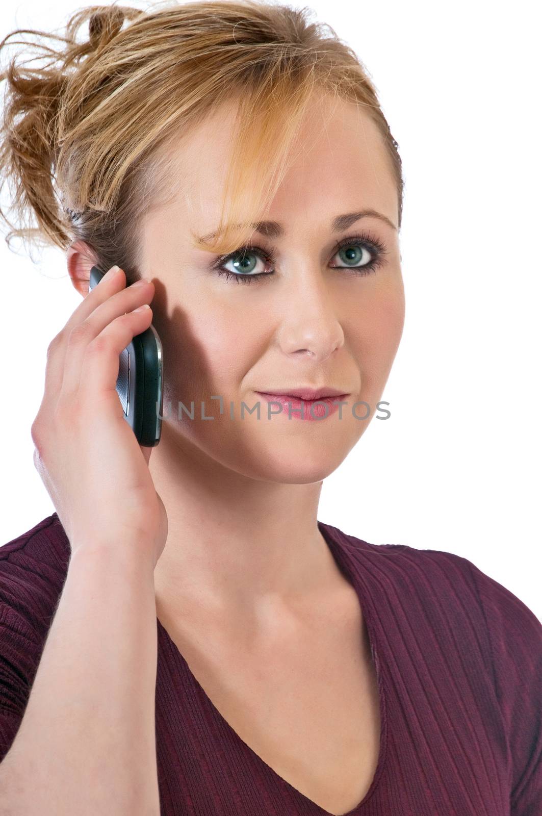 Young woman with blonde hair listening to a friend talking on her cell-phone.
