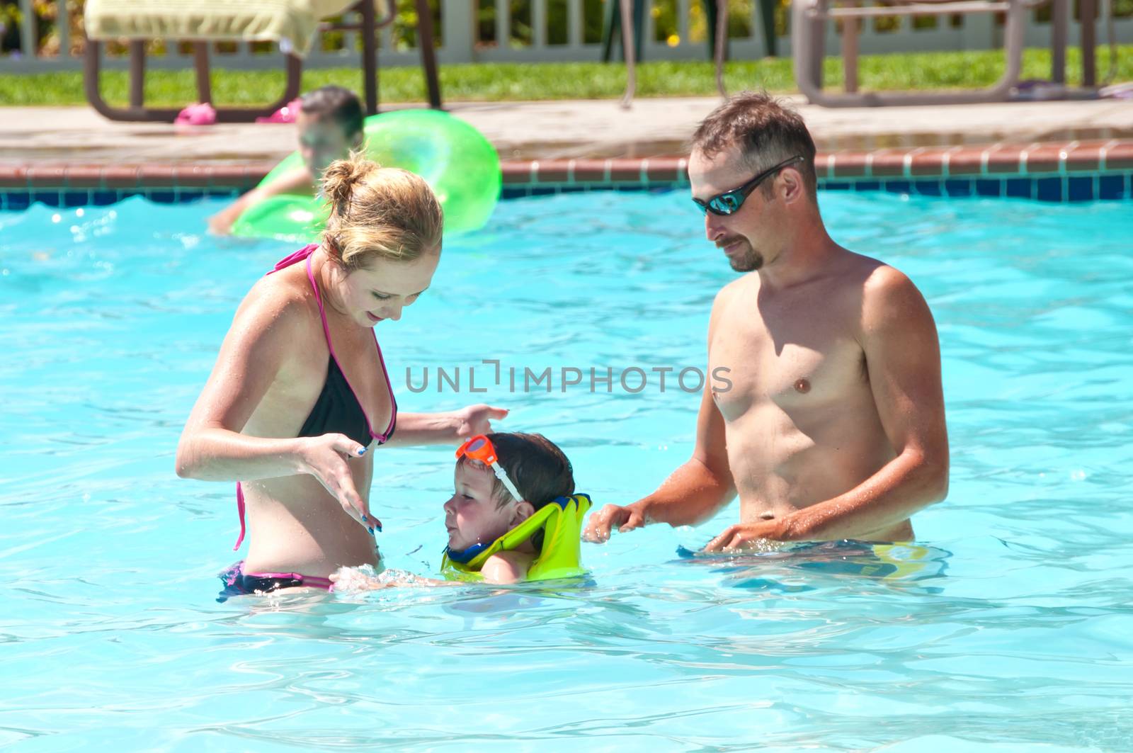 Young man and woman showing their son how to swim