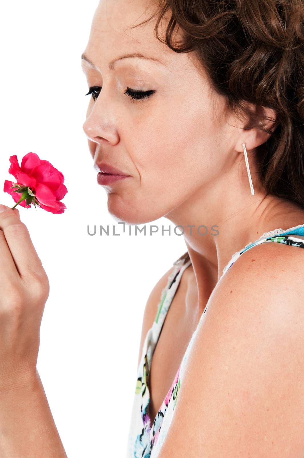 Beautiful young woman enjoying the fragrance of a fresh rose flower.