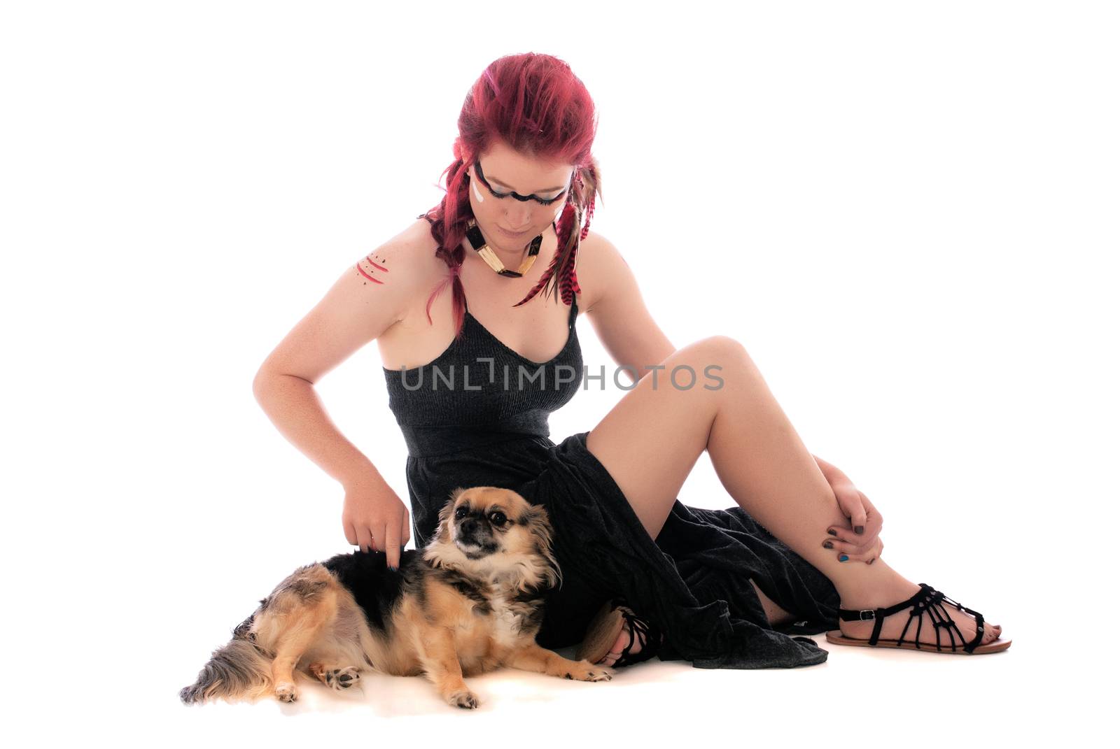 Pretty young girl dressed as a native american indian seated on the ground with her pet Chihuahua.