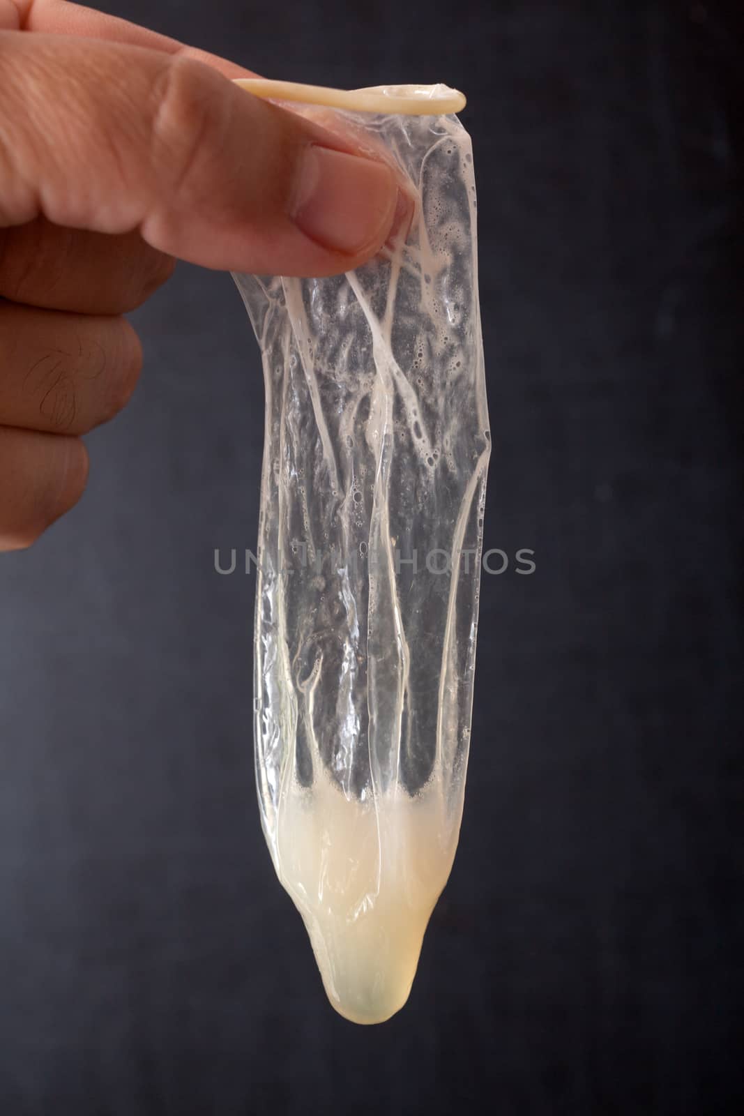 Hand with used condom isolated on black background