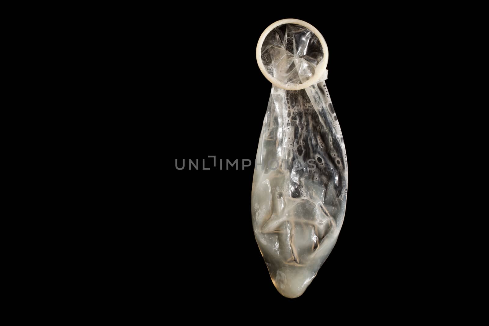 Used condom with sperm on black background