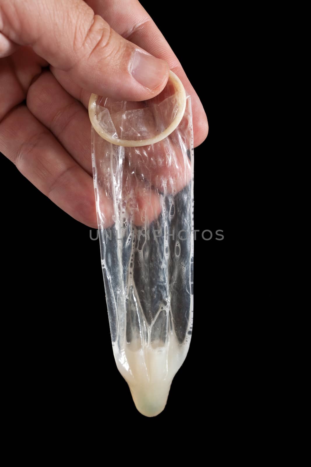 Hand with used condom isolated on black background