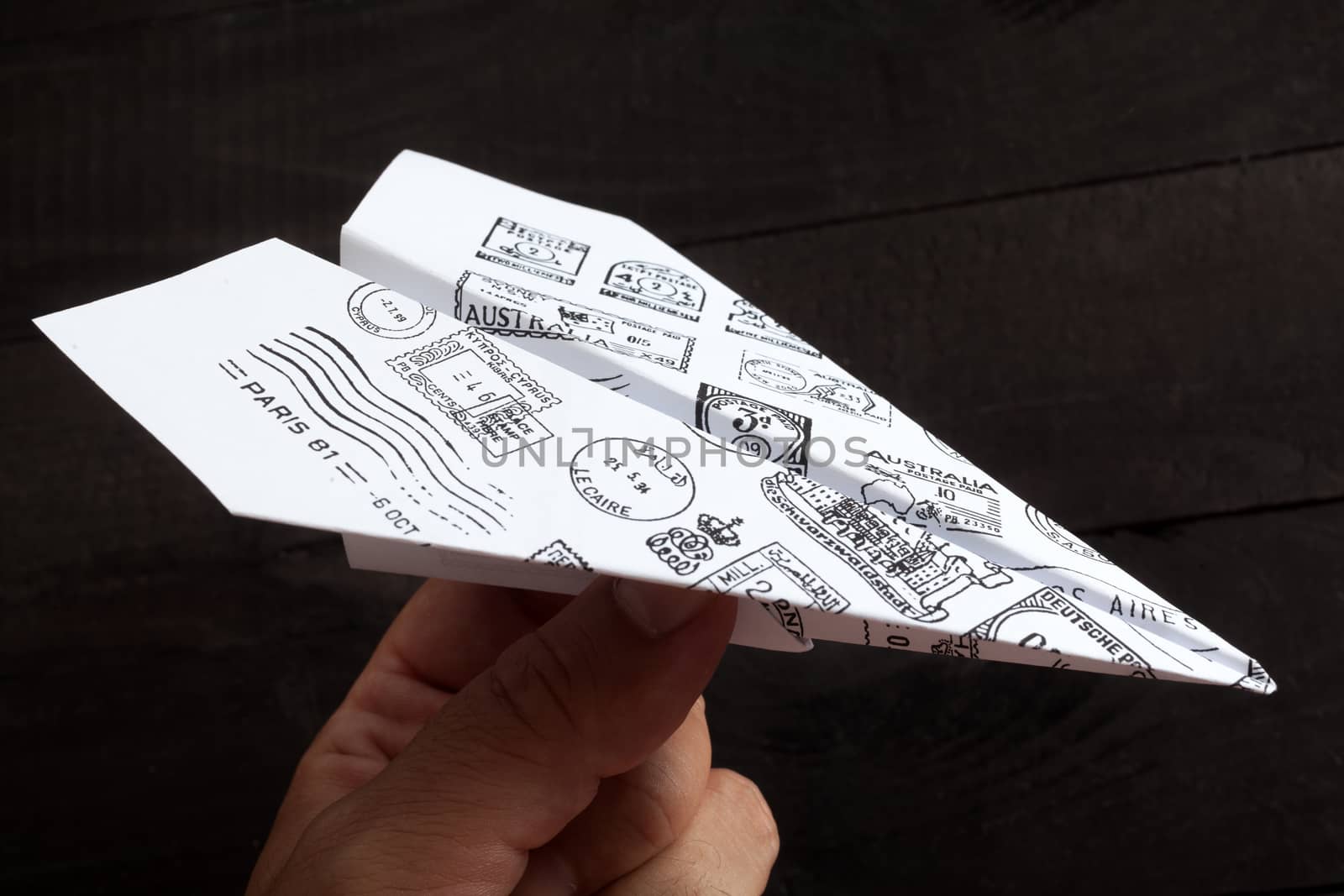 Paper airplane with mail stamps on black background