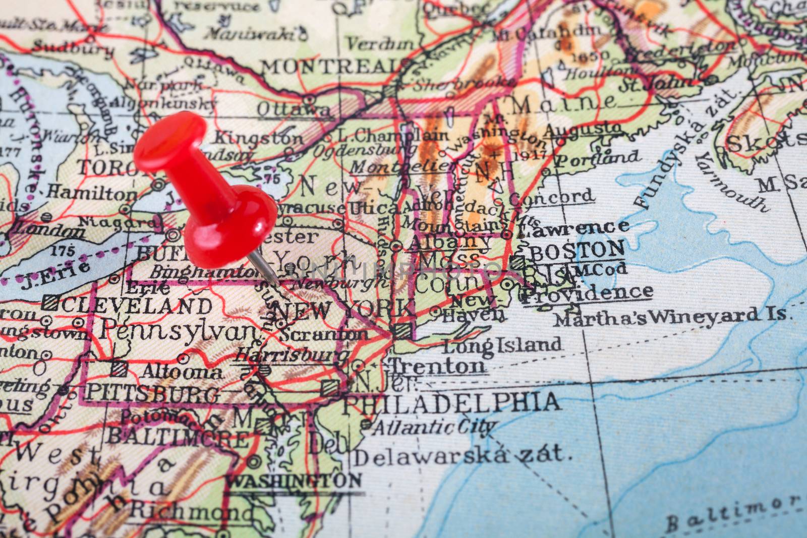 Red push pin showing the location of a destination point on a map. New York