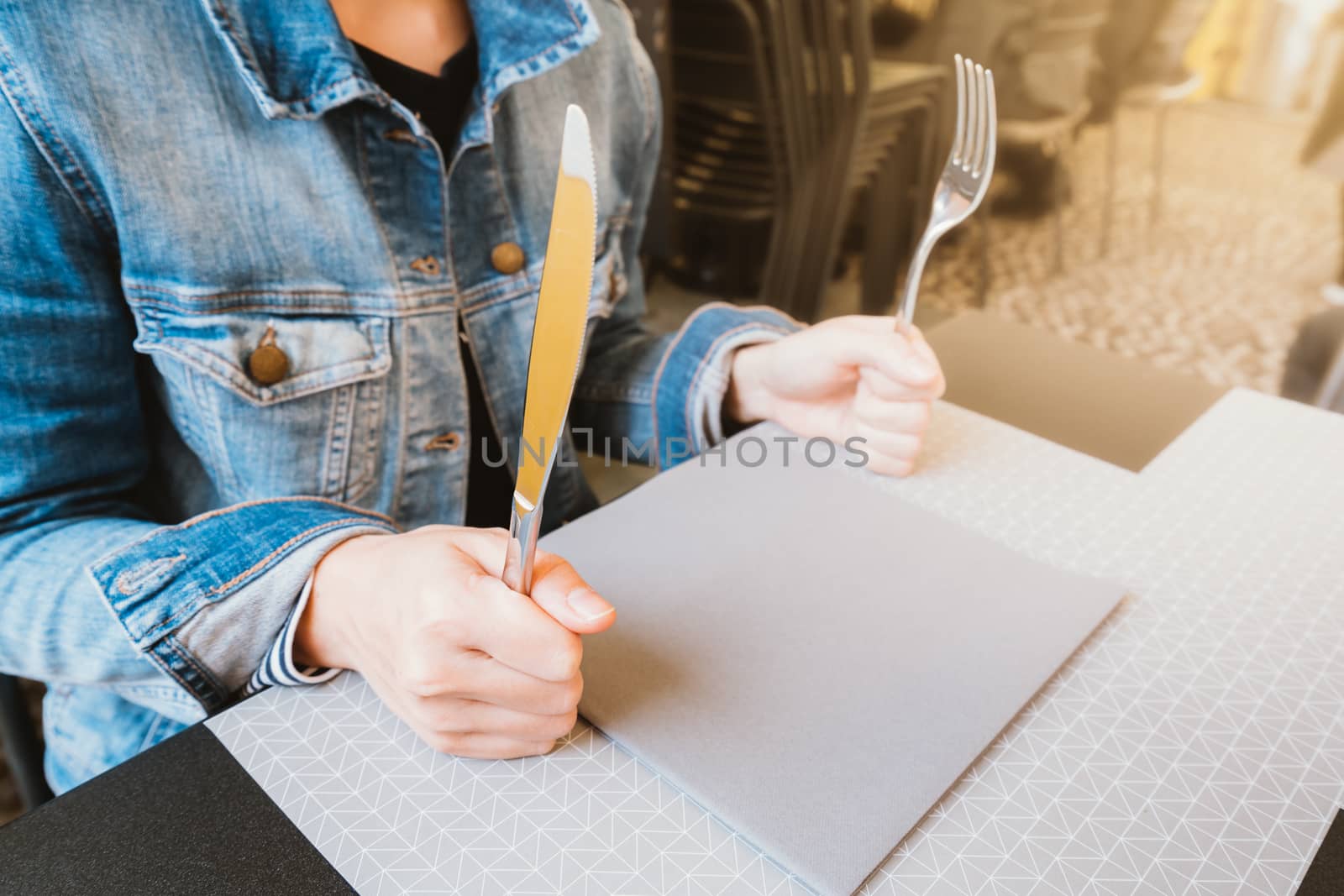 Hungry woman holding knife and fork, waiting for food, food or restaurant concept, warm light tone