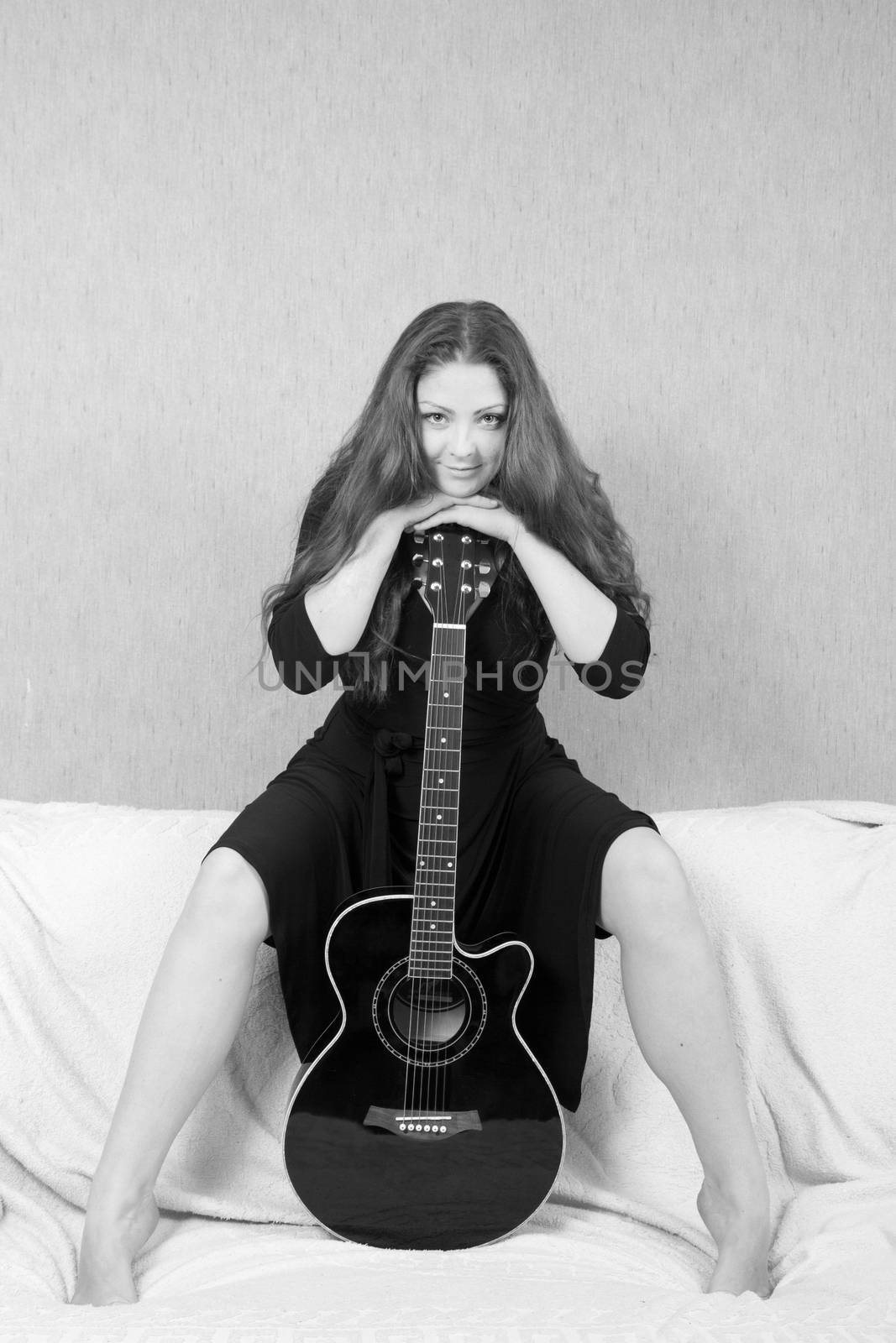 Beautiful woman with a guitar on a black background