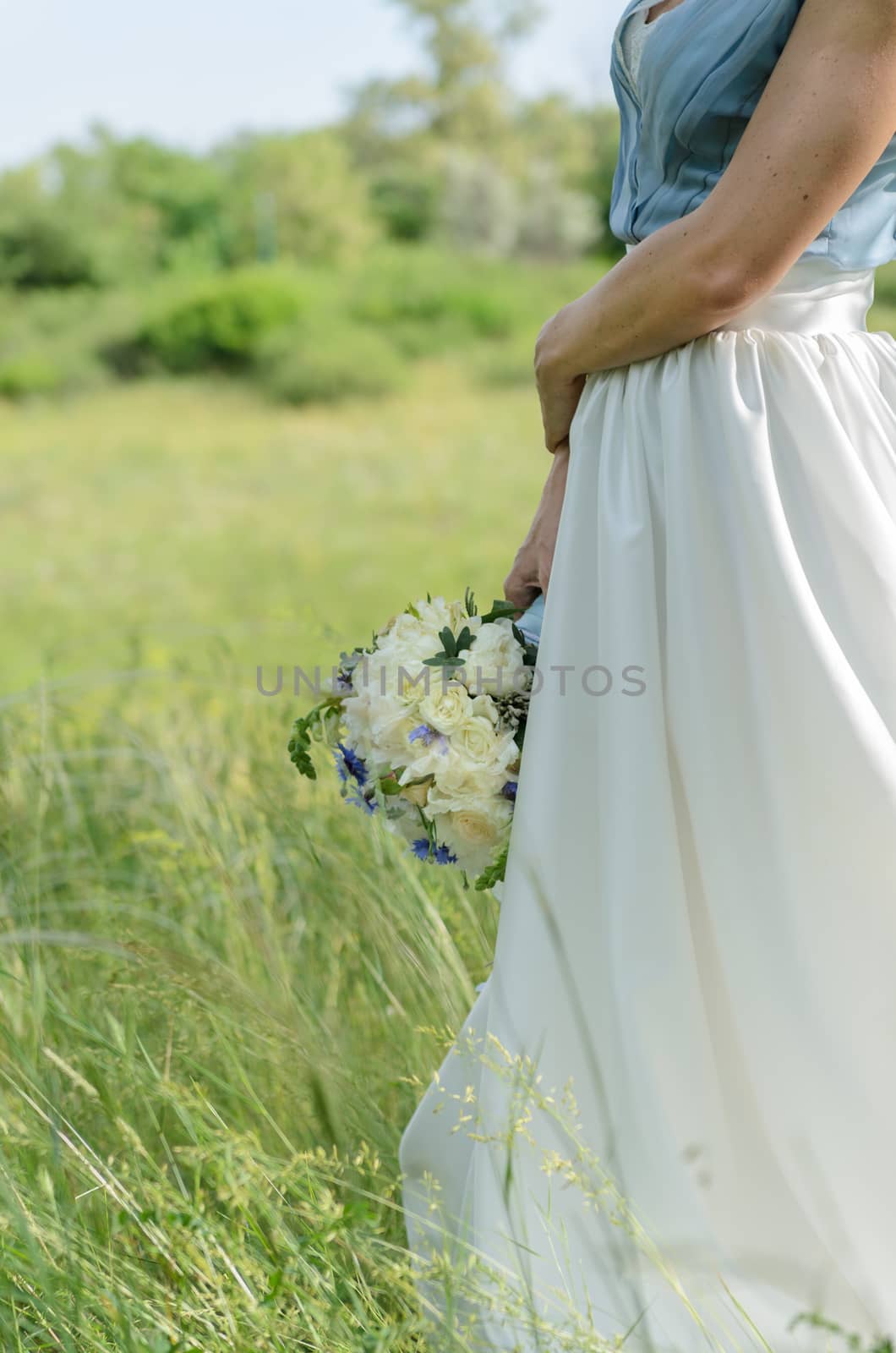 bride with a bouquet in green grass
