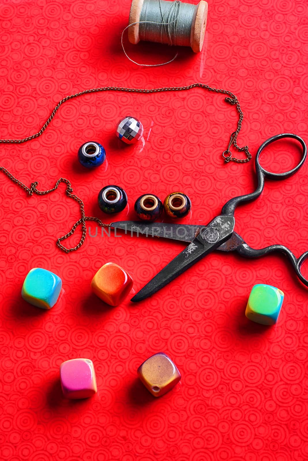 beads for needlework and scissors on bright red background