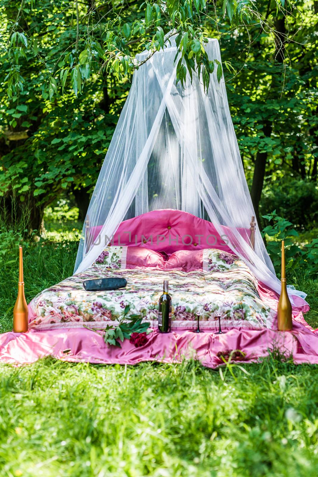 Bed with red blanket in the garden for lovers