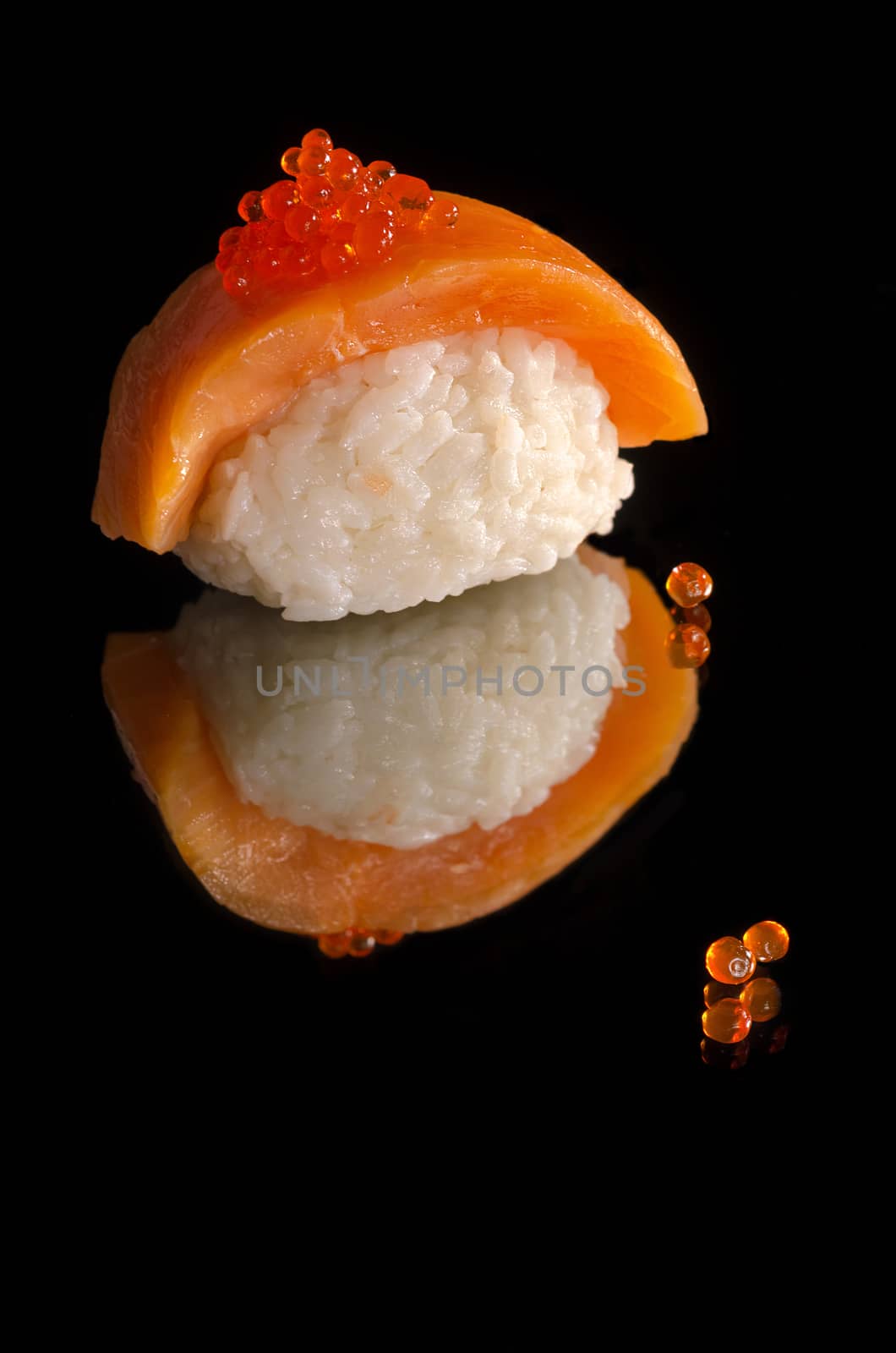 Sushi with salmon and caviar on black background with reflection