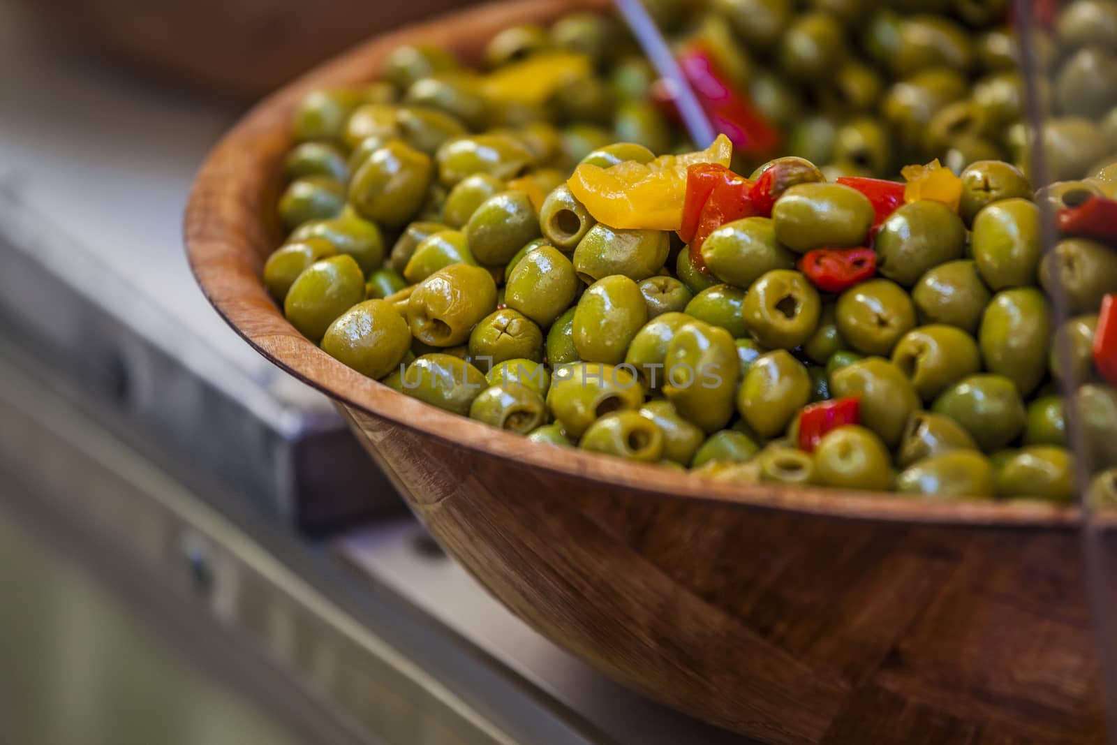 Close-up of green olives with red and yellow pepperoni in a dish