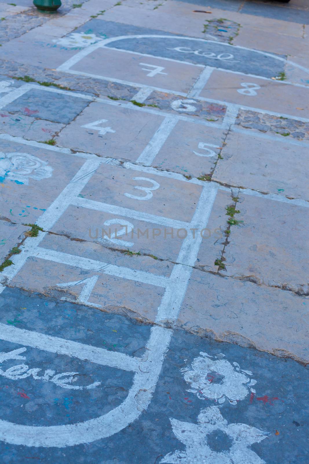 Hopscotch on an asphalt floor with chalk drawings of numbers and squares as an icon of youth innocence and children playing a fun jumping game at recess or after elementary school.