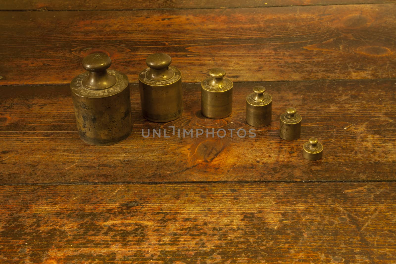 Different vintage brass weights unit on wood floor background