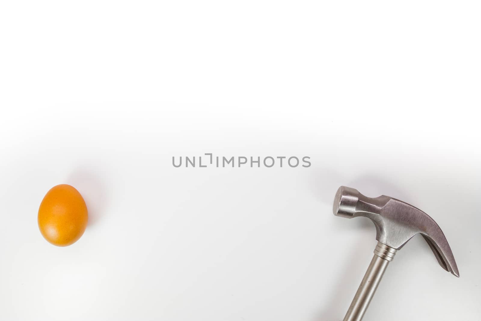 Hammer hitting a egg isolated on white with copy space.