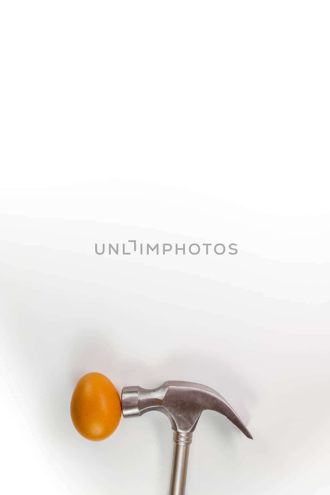 Hammer hitting a egg isolated on white with copy space.
