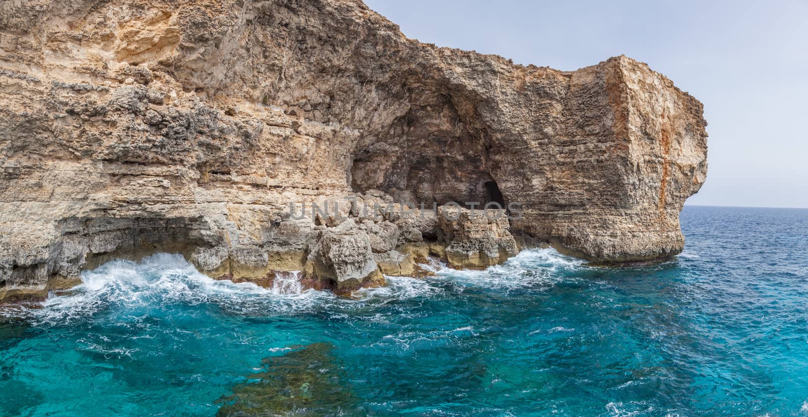 Huge multi colours rocks over a ligth blue water in mediterranean sea