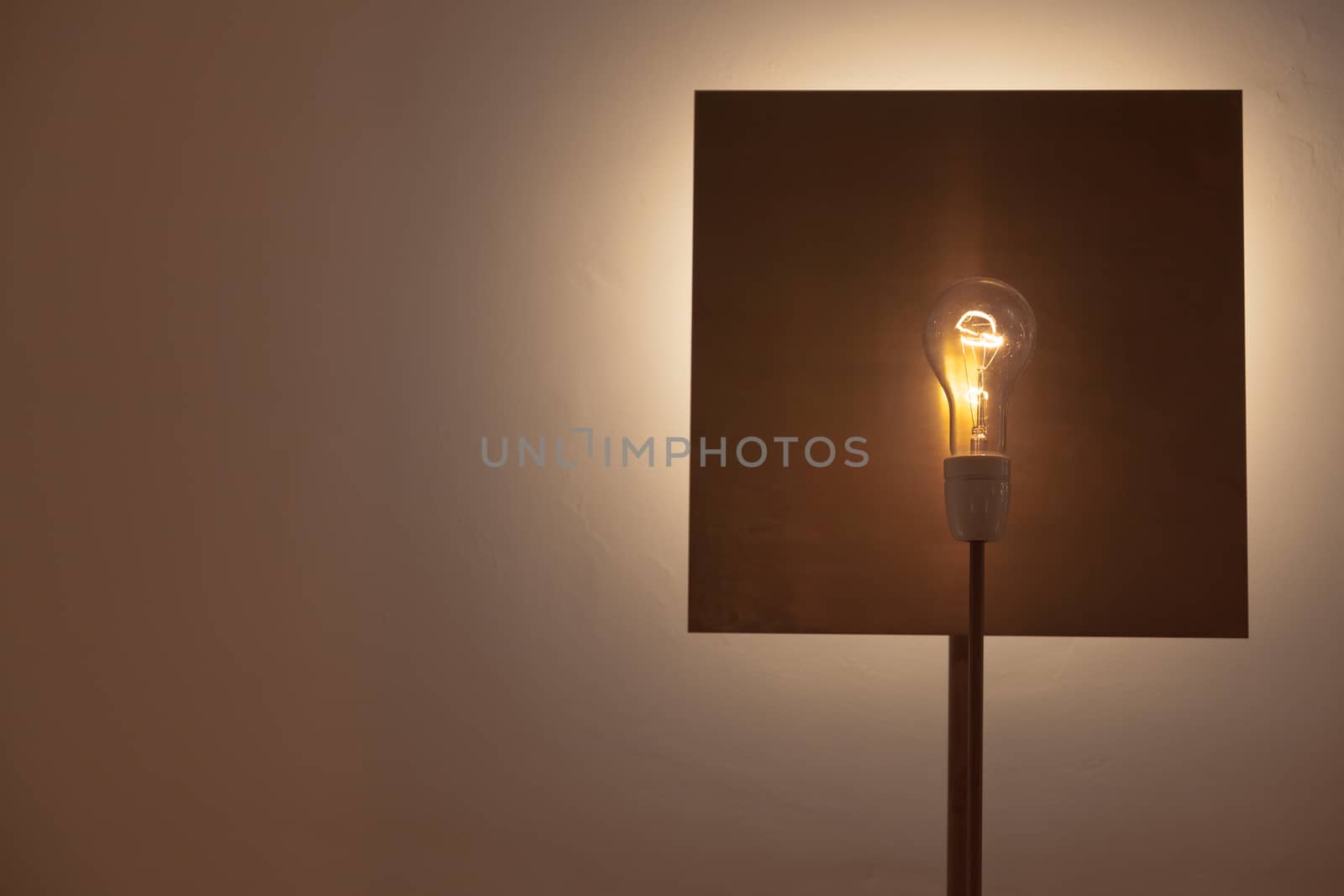 A lamp made with a lamp over a square shaped copper background