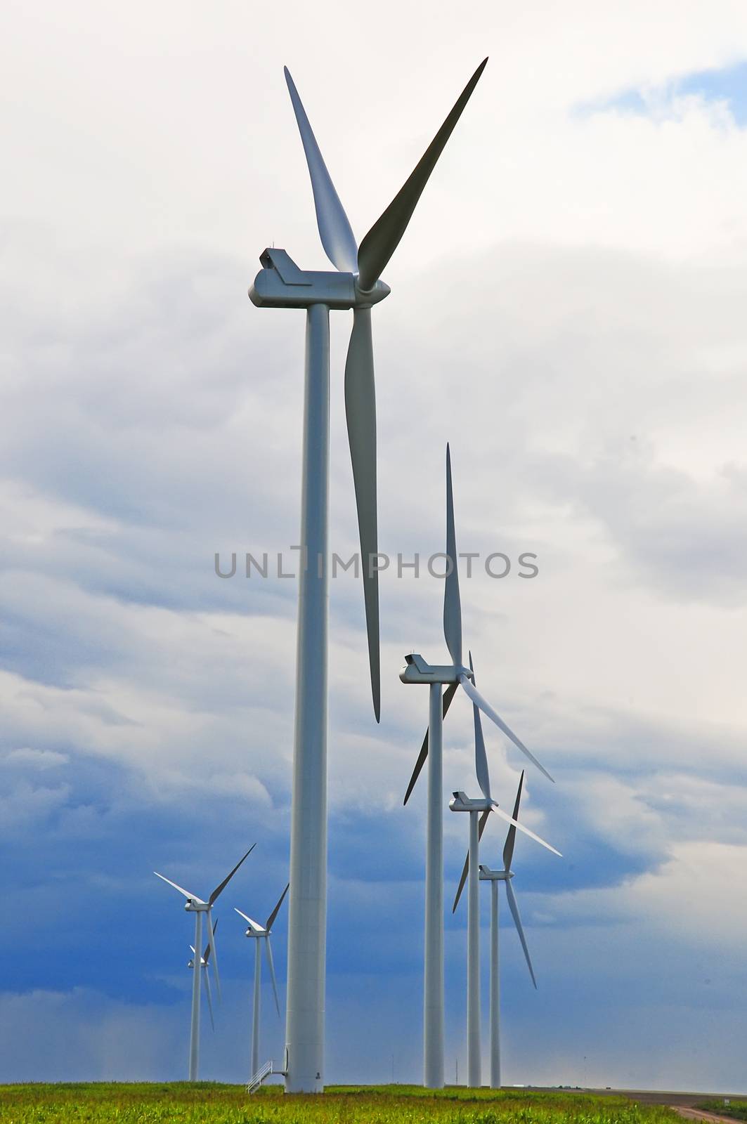 Wind turbines against a cloudy sky await a breath of wind to start thier turbines.