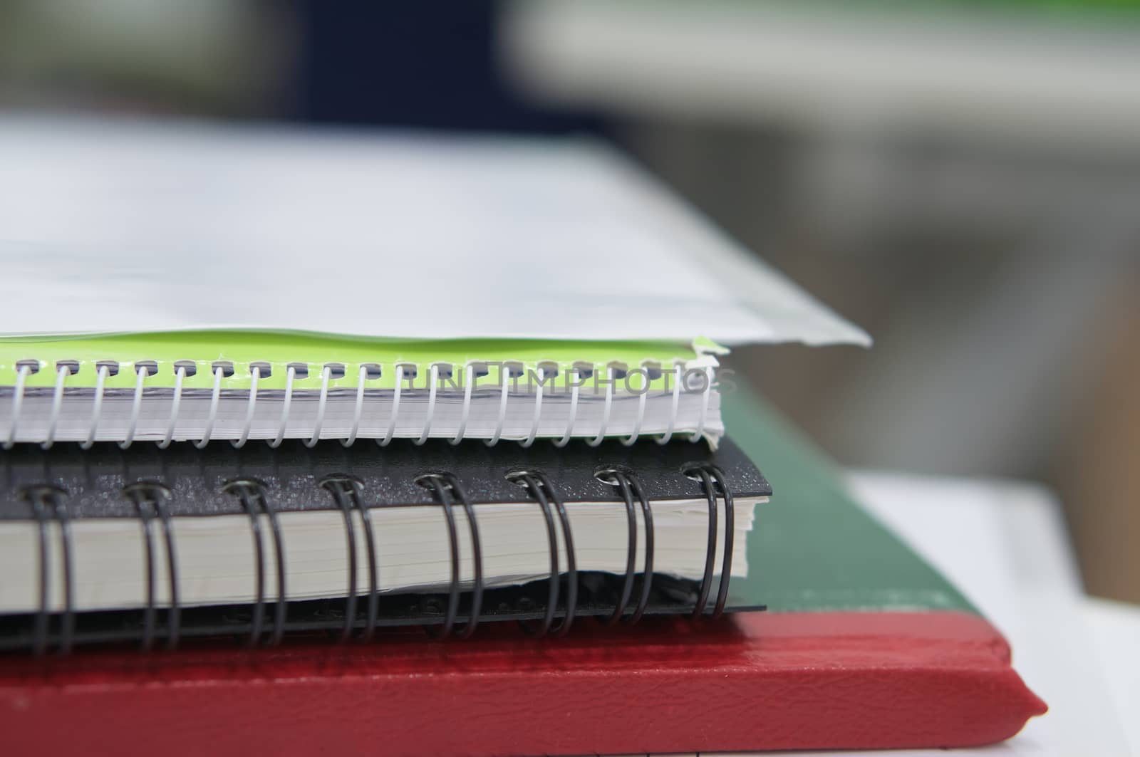 Stack of notebook and file document on white desk at office.