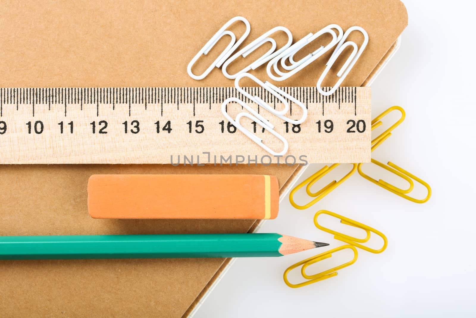 notebook, eraser, ruler, pencil and paperclips on white background